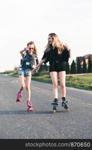 Teenage smiling happy girls having fun rollerskating together on summer day