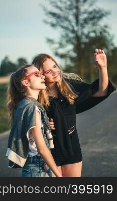 Teenage smiling happy girls having fun walking outdoors, hanging, spending time together on summer day