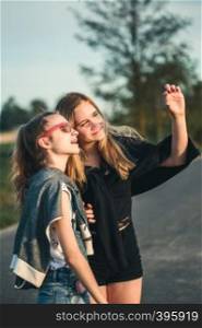 Teenage smiling happy girls having fun walking outdoors, hanging, spending time together on summer day