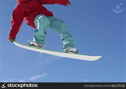 Teenage snowboarder jumping, cropped