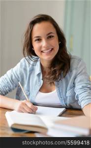 Teenage student girl studying at home smiling at camera