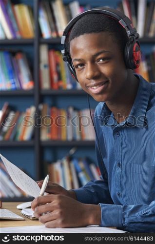 Teenage Student Wearing Headphones Whilst Working In Library