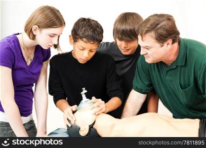 Teenage students and their teacher, using an oxygen mask on a CPR dummy.