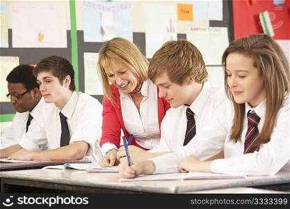 Teenage Students Studying In Classroom With Teacher