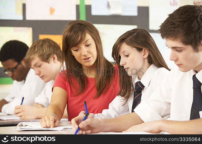 Teenage Students Studying In Classroom With Teacher