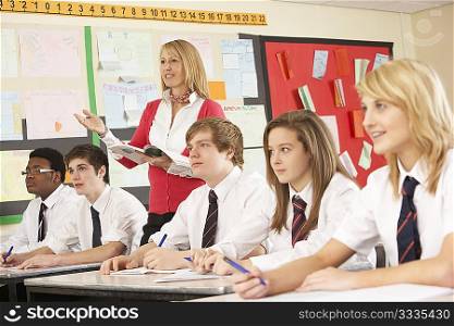 Teenage Students Studying In Classroom With Teacher
