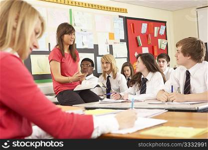 Teenage Students Studying In Classroom With Teacher And Assistant