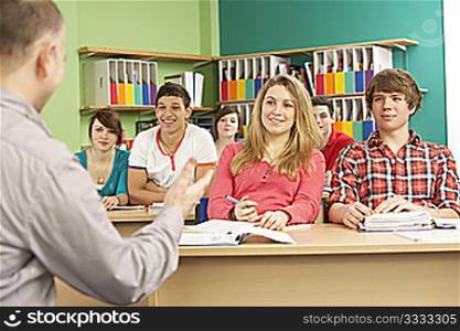 Teenage Students Studying In Classroom With Tutor