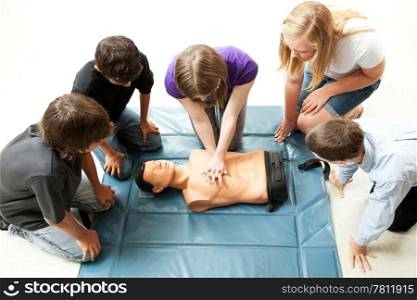 Teenage students use a mannequin to practice life saving techniques.