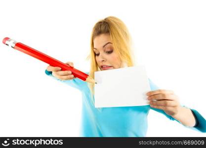 Teenage thinking woman writing some notes on piece of paper using big oversized pencil.. Woman with big pencil writing on paper