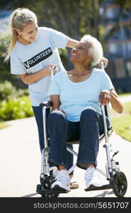 Teenage Volunteer Pushing Senior Woman In Wheelchair