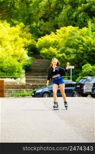 Teenage woman girl riding roller skates during summertime through city having great time.. Young woman riding roller skates
