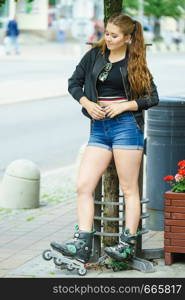 Teenage woman girl riding roller skates during summertime through city having great time.. Young woman riding roller skates