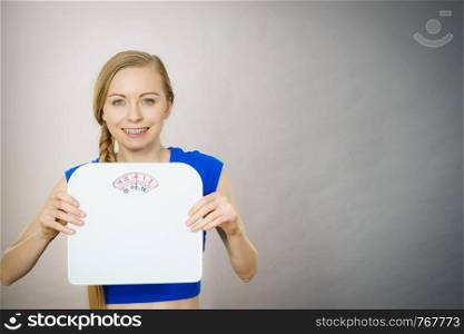 Teenage woman holding bathroom scale machine thinking about weight loss and proper body mass. Being fit and healthy concept.. Teenage woman holding bathroom scale machine