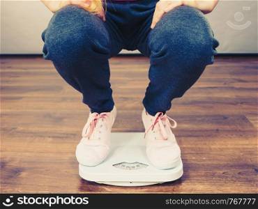 Teenage woman on bathroom scale machine thinking about weight loss and proper body mass. Being fit and healthy concept.. Teenage woman on bathroom scale machine
