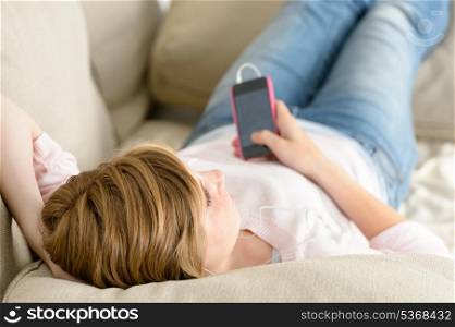 Teenage woman relax on sofa listen music on her cellphone