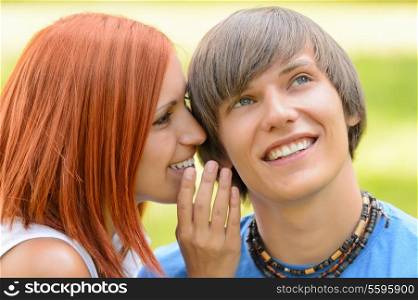 Teenage woman whispering to her boyfriend loving couple summer time