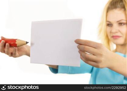 Teenage woman writing some notes on piece of paper using big oversized pencil.. Woman with big pencil writing on paper