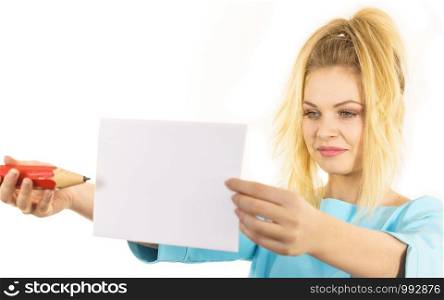 Teenage woman writing some notes on piece of paper using big oversized pencil.. Woman with big pencil writing on paper