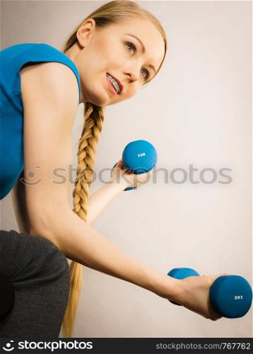 Teenage young woman working out at home with small light dumbbells. Training at home, being fit and healthy.. Teenage woman working out at home with dumbbell