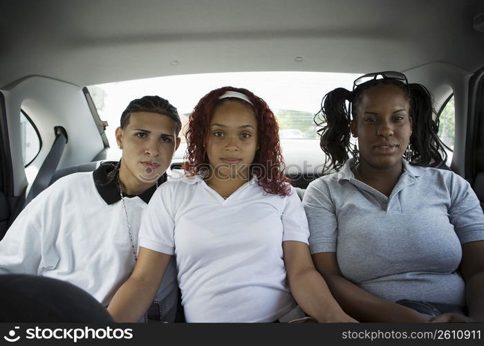 Teenaged friends sitting in back seat of car
