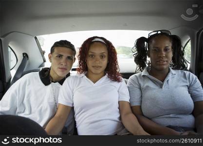 Teenaged friends sitting in back seat of car