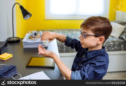 Teenager applying hand sanitizer before doing homework in his bedroom