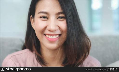 Teenager Asian woman feeling happy smiling and looking to camera while relax in living room at home. Lifestyle beautiful Asian young female using relax time at home concept.