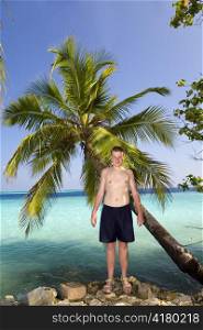 Teenager at palm tree and ocean in the background
