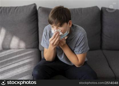 teenager boy blowing his nose while being quarantined