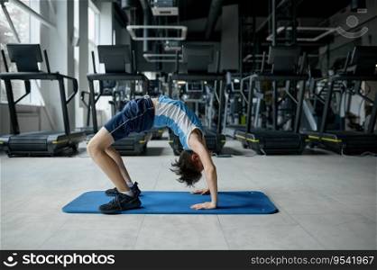 Teenager boy doing gymnastics exercise standing in bridge yoga position. Fitness, flexibility and childhood. Teenager boy doing gymnastics exercise standing in bridge position