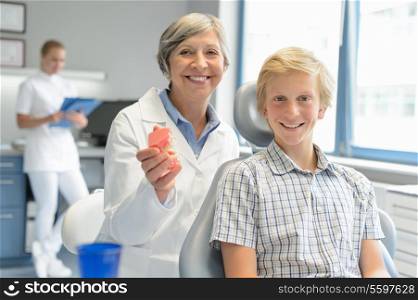 Teenager boy patient dentist hold teeth dentures dental assistant office