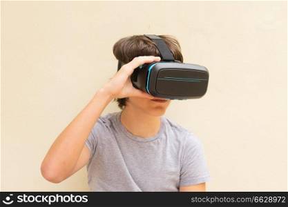 Teenager boy wearing and holding VR virtual realty glasses. Teenager wearing VR glasses