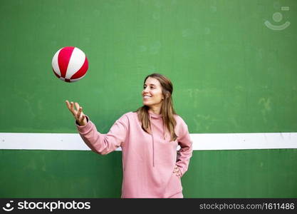 Teenager female playing basketball over green wall