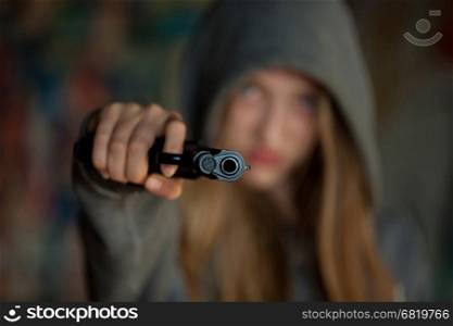 Teenager Girl Aiming a gun at the camera, blurred focus