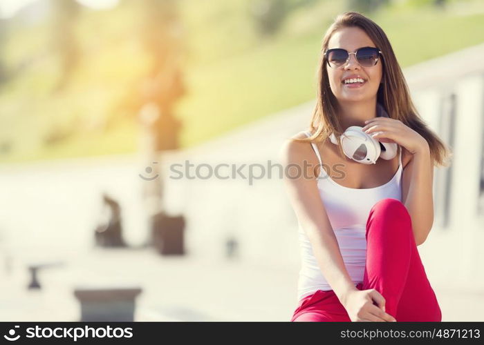 Teenager girl having time in outdoors. Attractive brunette girl in summer park enjoying daytime wearing headphones