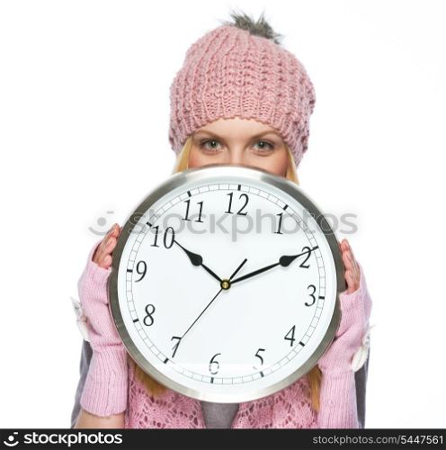 Teenager girl in winter hat and scarf hiding behind clock