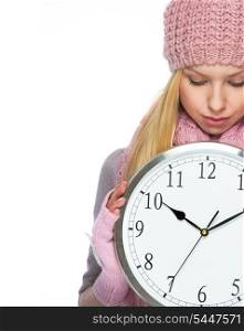Teenager girl in winter hat and scarf showing clock