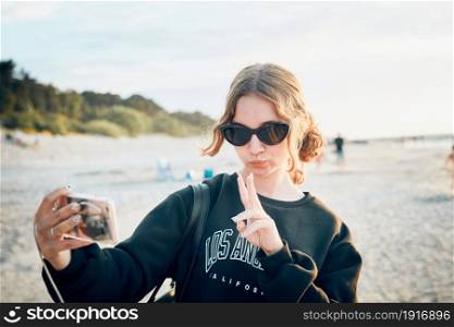 Teenager girl making gesture during video call on smartphone. Young woman taking selfie photos during trip on summer vacation