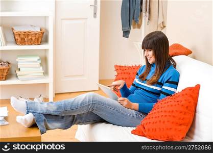 Teenager girl relax home - sitting on sofa with touch screen tablet computer