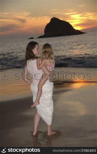 Teenager holding a child on the beach