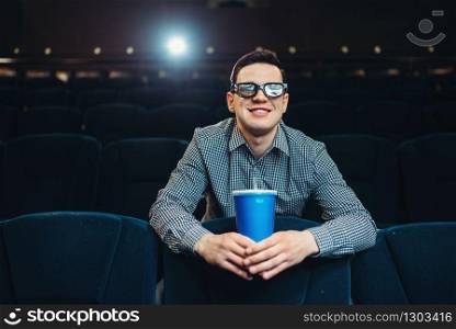 Teenager in 3d glasses holds beverage and poses in cinema. Showtime, entertainment industry