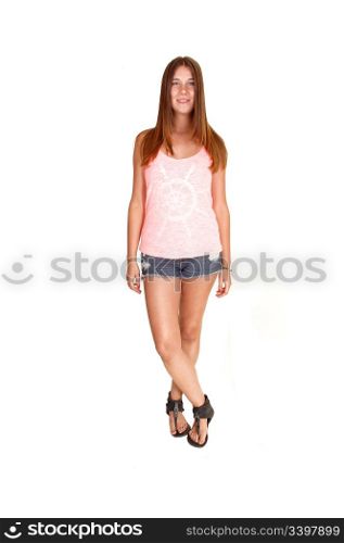 Teenager in jeans shorts and pink top standing relaxed in the studiofor white background.