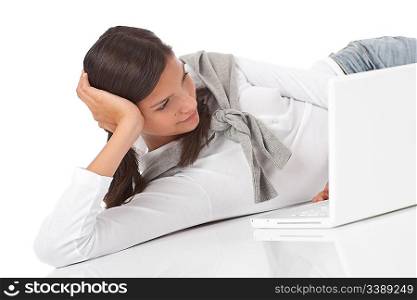 Teenager lying down with laptop on white background