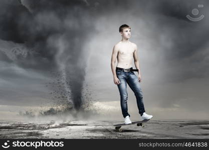 Teenager on skateboard. Skater in jeans on road with tornado at background