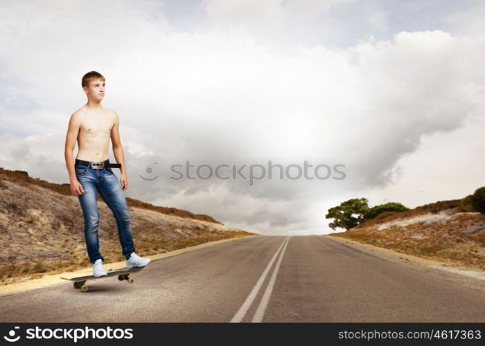 Teenager on skateboard. Young skater in jeans riding on road