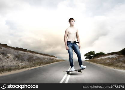 Teenager on skateboard. Young skater in jeans riding on road