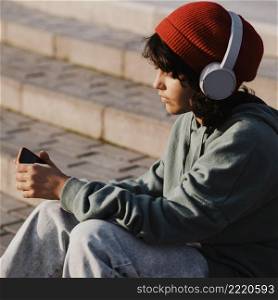 teenager outdoors using smartphone listening music headphones