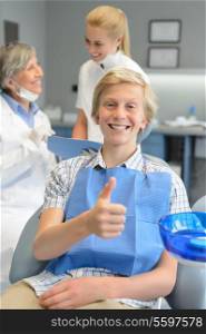 Teenager patient thumbup at dental surgery dentist and nurse background