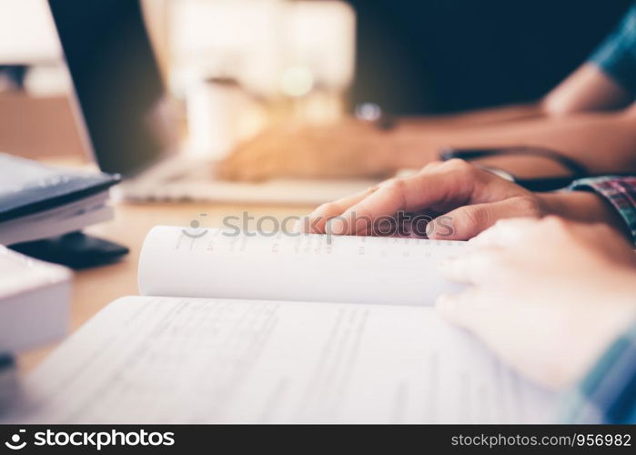 Teenager reading textbook in library.